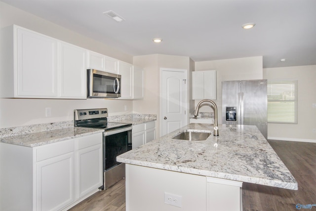 kitchen with hardwood / wood-style flooring, appliances with stainless steel finishes, white cabinetry, sink, and a center island with sink