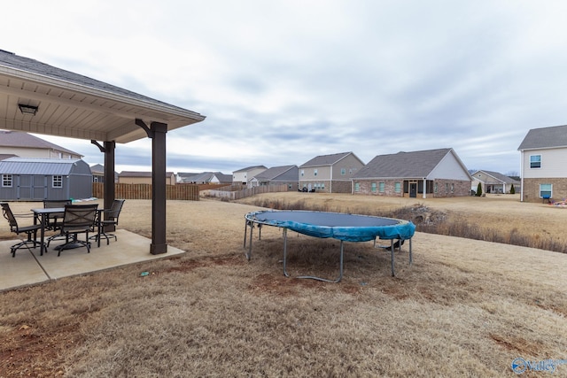 view of yard with a patio, a trampoline, and a storage shed