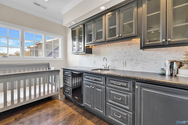 bar featuring visible vents, a sink, tasteful backsplash, dark wood finished floors, and crown molding