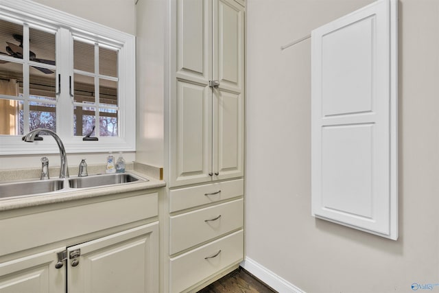 kitchen featuring dark wood-style flooring, light countertops, baseboards, and a sink