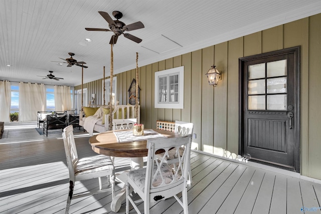 wooden terrace with outdoor dining area and a ceiling fan