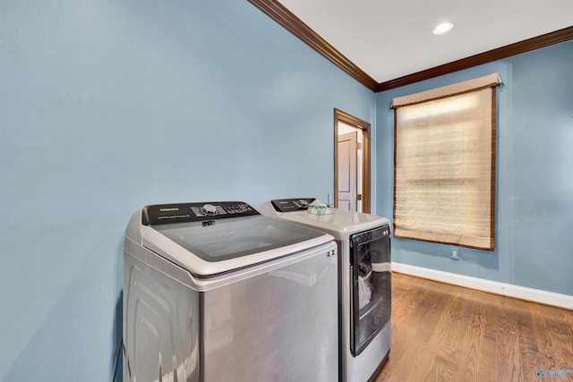 washroom with crown molding, baseboards, laundry area, wood finished floors, and separate washer and dryer