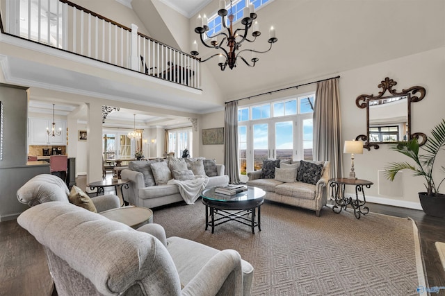 living room featuring a notable chandelier, ornamental molding, wood finished floors, a high ceiling, and baseboards