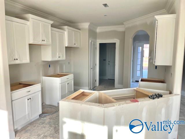 kitchen featuring white cabinetry, a center island, and ornamental molding