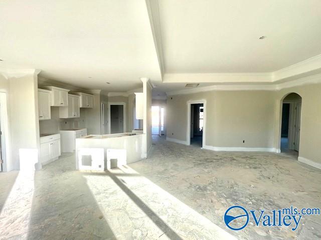 interior space featuring white cabinets, a breakfast bar, a raised ceiling, and crown molding