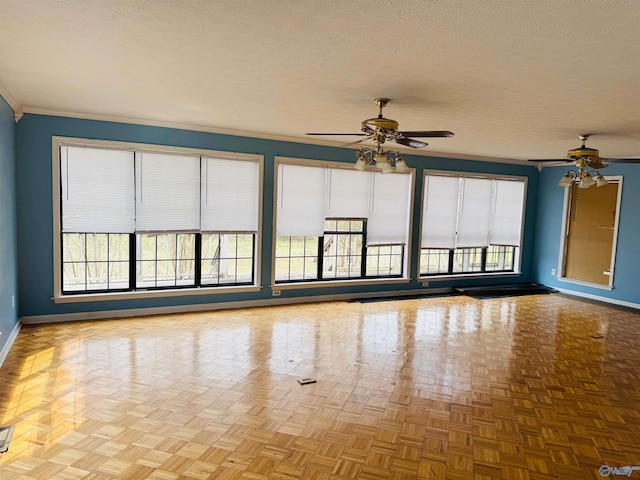 spare room featuring a textured ceiling, ornamental molding, a ceiling fan, and baseboards