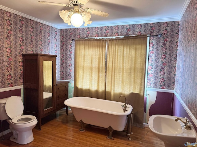 bathroom with a soaking tub, wainscoting, crown molding, and wallpapered walls