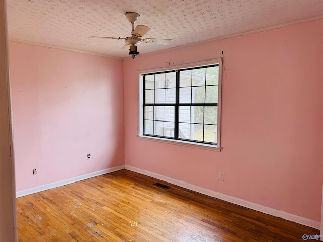 unfurnished room featuring hardwood / wood-style flooring, a textured ceiling, baseboards, and a ceiling fan