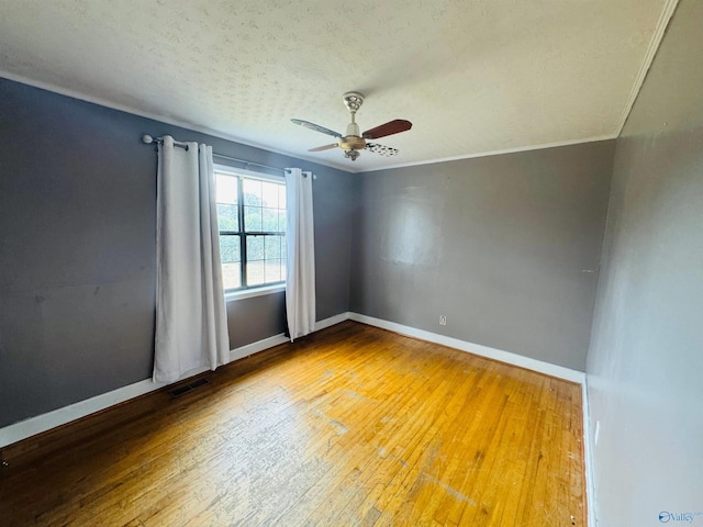 empty room featuring baseboards, crown molding, visible vents, and hardwood / wood-style floors