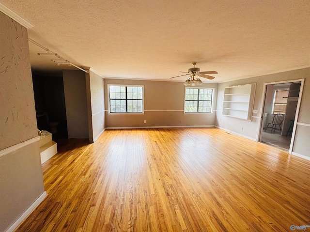 unfurnished room featuring a textured ceiling, baseboards, wood finished floors, and built in features