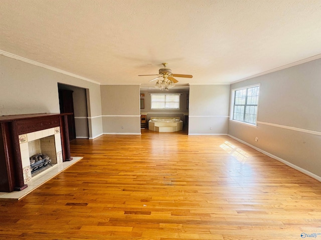 unfurnished living room with a textured ceiling, baseboards, a tile fireplace, and light wood-style floors