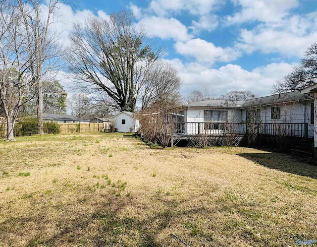 view of yard featuring a deck, a storage unit, an outdoor structure, and fence