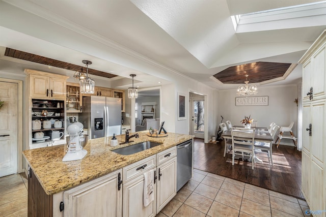 kitchen featuring appliances with stainless steel finishes, light wood-type flooring, a kitchen island with sink, sink, and decorative light fixtures