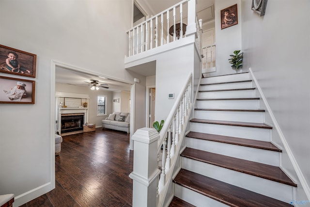 stairway featuring hardwood / wood-style floors, ceiling fan, and a high ceiling