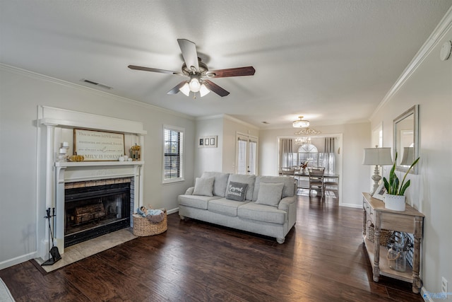 living room featuring dark hardwood / wood-style flooring, a textured ceiling, ceiling fan, crown molding, and a fireplace