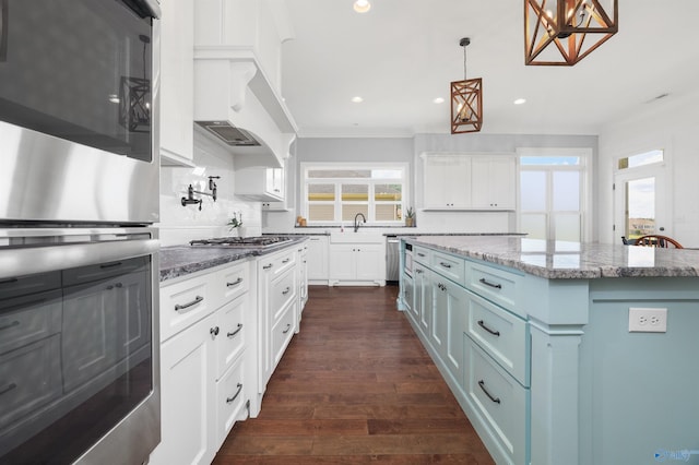 kitchen featuring a center island, hanging light fixtures, appliances with stainless steel finishes, dark wood-type flooring, and white cabinetry