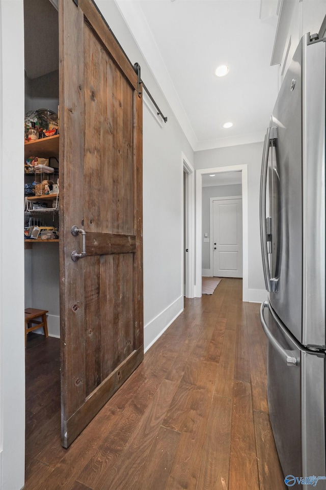 hallway with a barn door, baseboards, dark wood finished floors, and crown molding