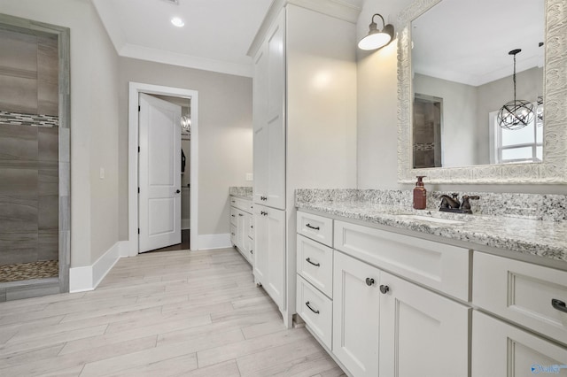 bathroom with baseboards, tiled shower, wood finished floors, crown molding, and vanity