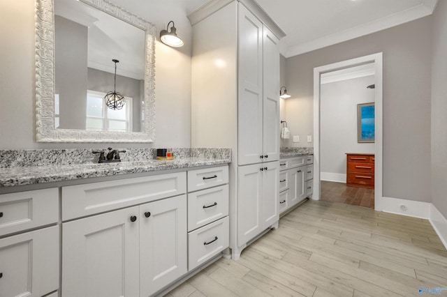 bathroom featuring ornamental molding, wood finished floors, and vanity