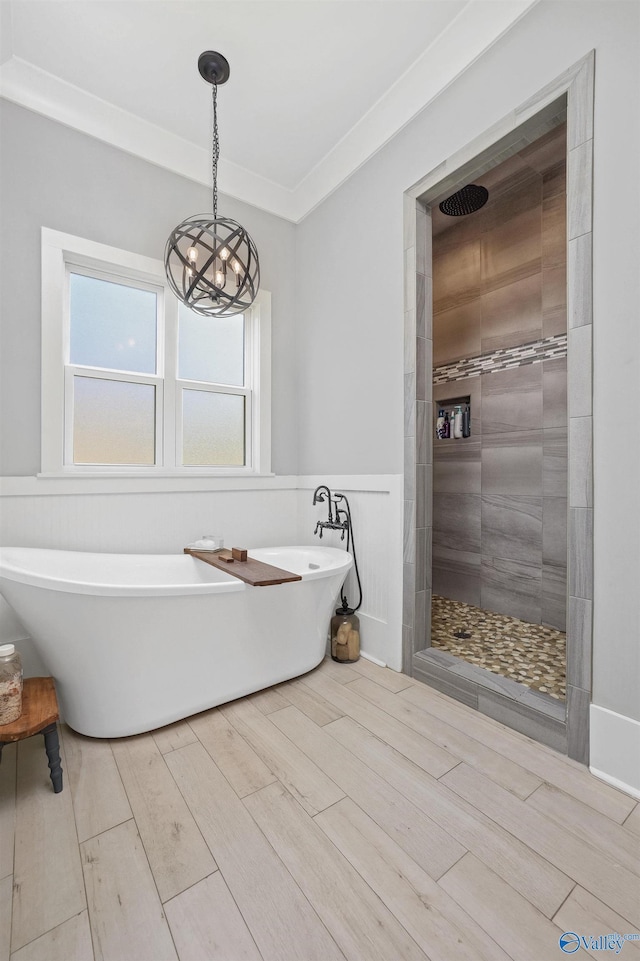 bathroom with a wainscoted wall, a soaking tub, ornamental molding, wood tiled floor, and tiled shower