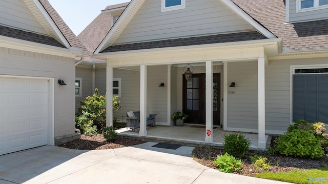 doorway to property featuring covered porch, a shingled roof, and an attached garage