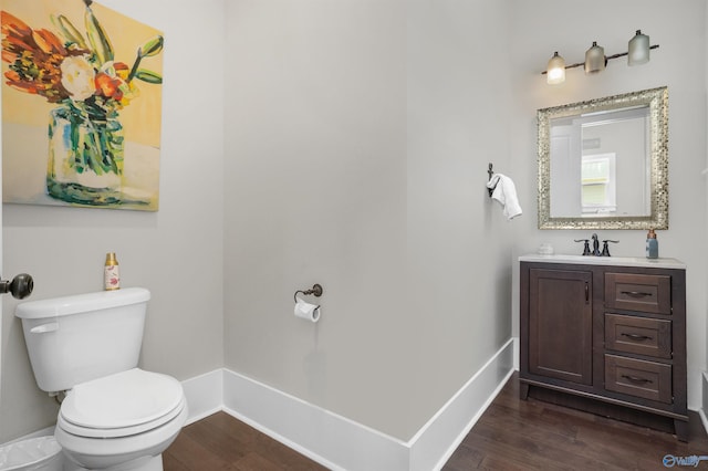 bathroom with baseboards, vanity, toilet, and wood finished floors