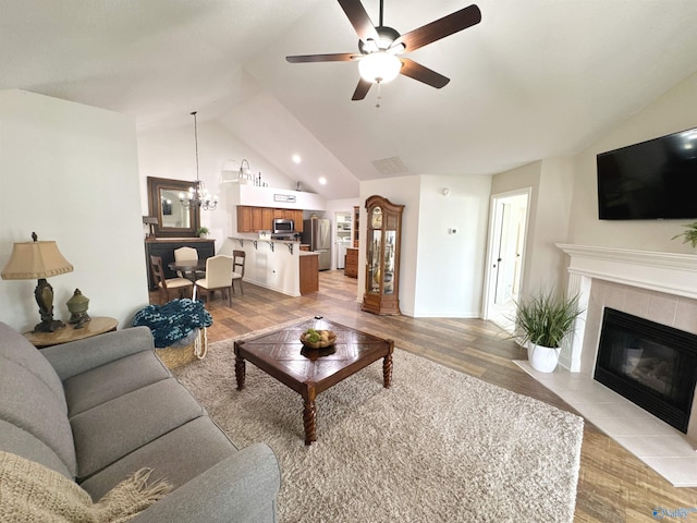 2072 Madison Villas Way Unit 2072, Madison, AL 35758 - living room featuring lofted ceiling, light wood-style floors, a ceiling fan, a fireplace, and a chandelier