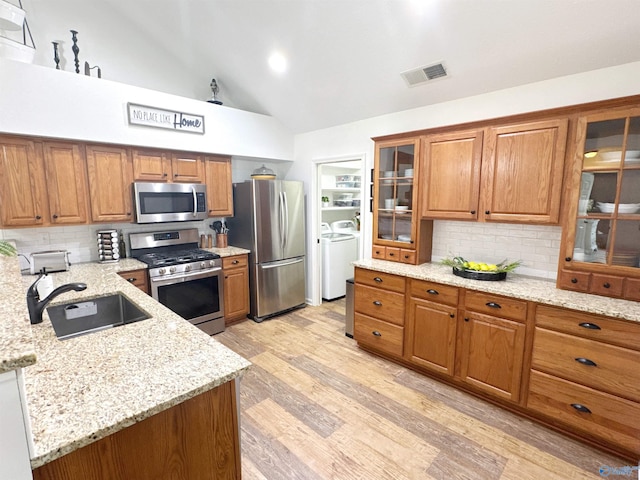 2072 Madison Villas Way Unit 2072, Madison, AL 35758 - kitchen with stainless steel appliances, a sink, separate washer and dryer, brown cabinetry, and backsplash