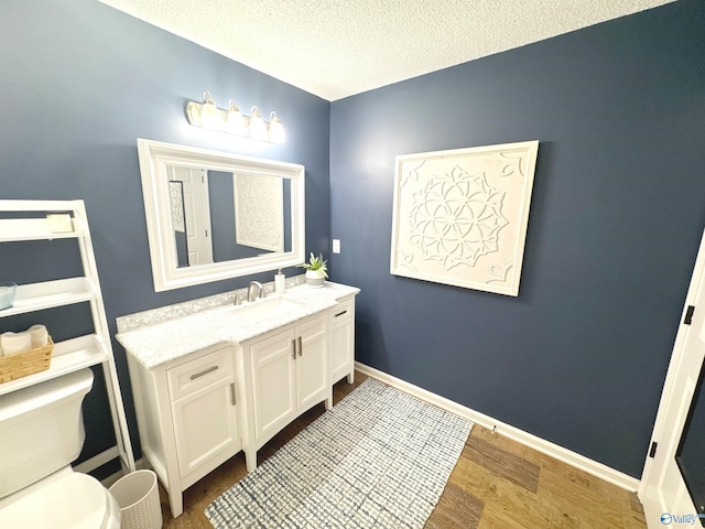 2072 Madison Villas Way Unit 2072, Madison, AL 35758 - bathroom featuring toilet, vanity, wood finished floors, a textured ceiling, and baseboards
