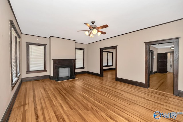 unfurnished living room featuring a multi sided fireplace, a healthy amount of sunlight, and light wood-type flooring