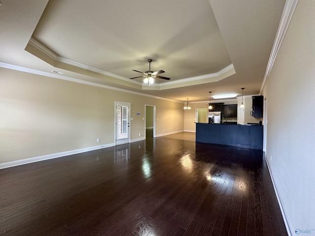 unfurnished living room with ceiling fan with notable chandelier, dark hardwood / wood-style flooring, a raised ceiling, and crown molding