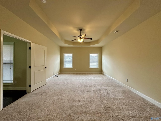 spare room featuring carpet flooring, a tray ceiling, and ceiling fan