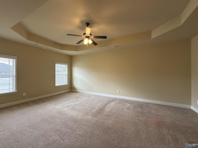 spare room featuring a tray ceiling, ceiling fan, and carpet