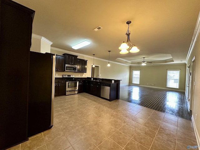 kitchen with sink, crown molding, a tray ceiling, decorative light fixtures, and stainless steel appliances