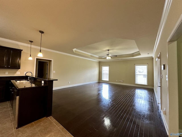 kitchen featuring ornamental molding, a raised ceiling, ceiling fan, sink, and hanging light fixtures