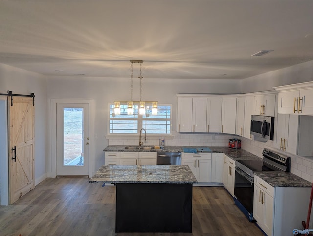 kitchen featuring tasteful backsplash, appliances with stainless steel finishes, a barn door, and a sink