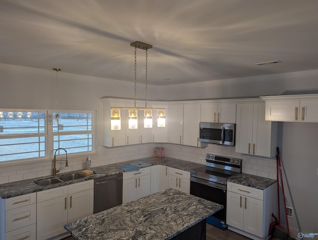 kitchen with tasteful backsplash, appliances with stainless steel finishes, white cabinetry, and a sink