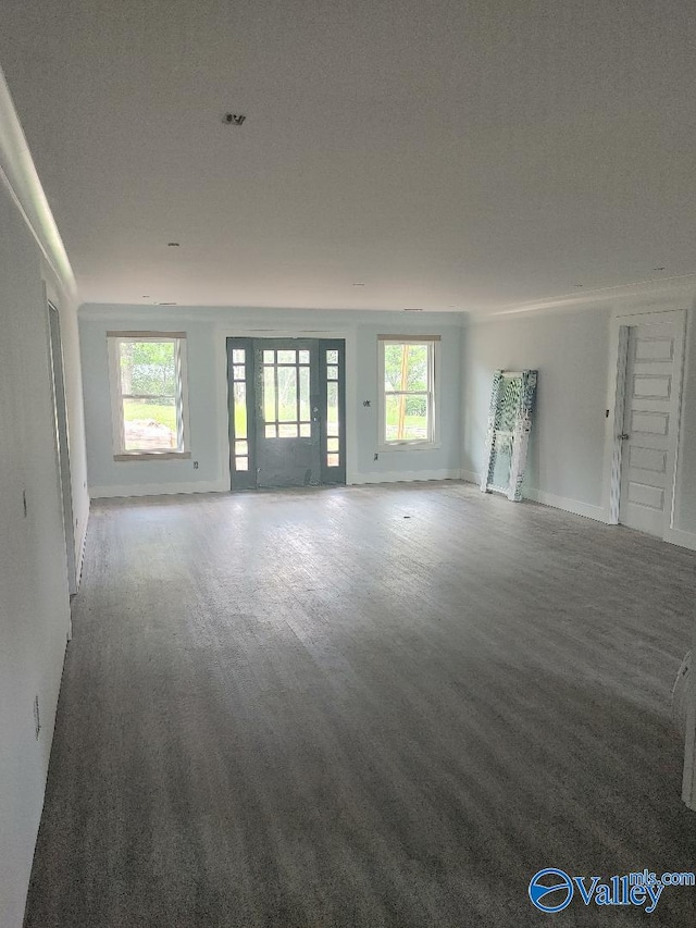 unfurnished living room featuring a healthy amount of sunlight and baseboards