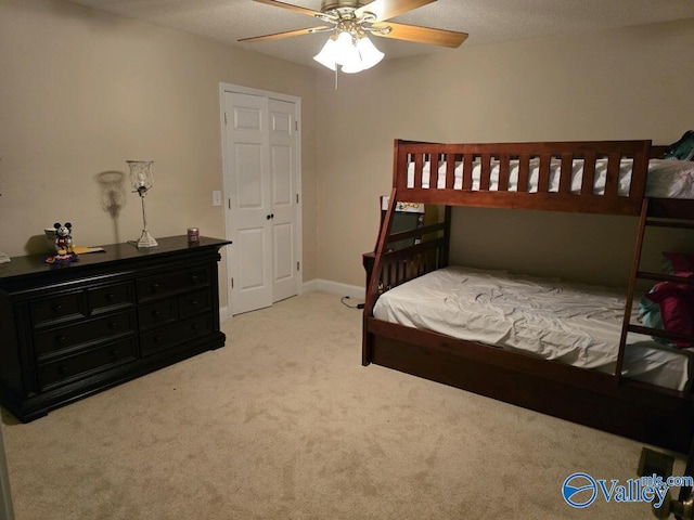 bedroom with light carpet, ceiling fan, and a textured ceiling