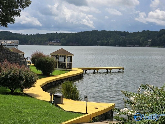 view of dock featuring central AC unit, a gazebo, a water view, and a lawn