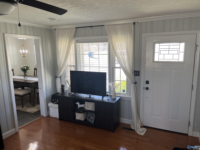 entryway featuring ceiling fan, a textured ceiling, dark hardwood / wood-style flooring, and ornamental molding