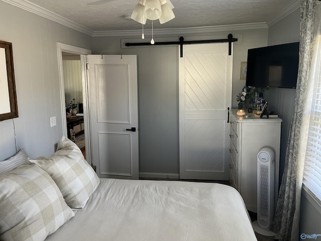 bedroom featuring ceiling fan, crown molding, a barn door, and a textured ceiling