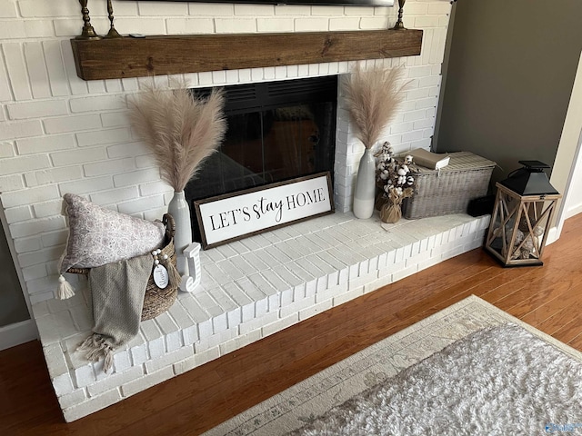 details with hardwood / wood-style flooring and a brick fireplace