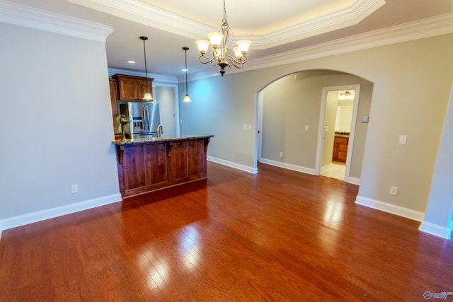 kitchen featuring stainless steel fridge with ice dispenser, a raised ceiling, decorative light fixtures, stone counters, and ornamental molding