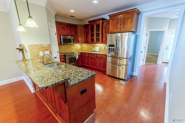 kitchen with kitchen peninsula, stainless steel appliances, tasteful backsplash, pendant lighting, and sink