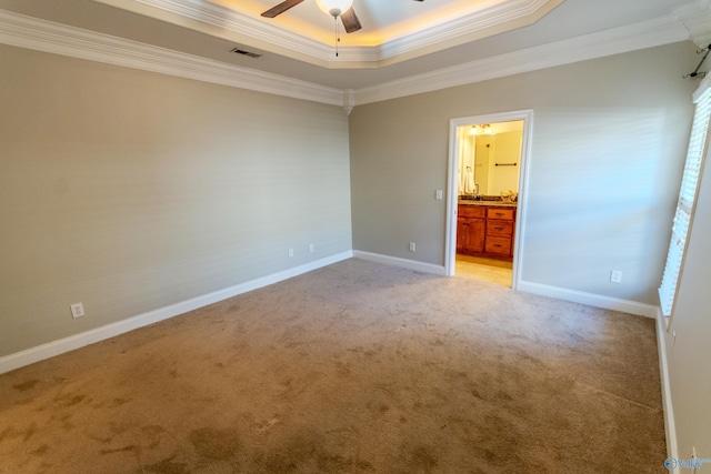 carpeted spare room with ceiling fan, a tray ceiling, and crown molding