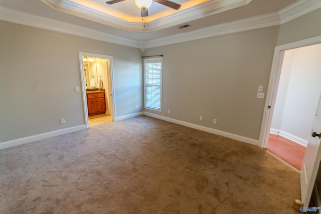 unfurnished room featuring a raised ceiling, light colored carpet, ceiling fan, and crown molding