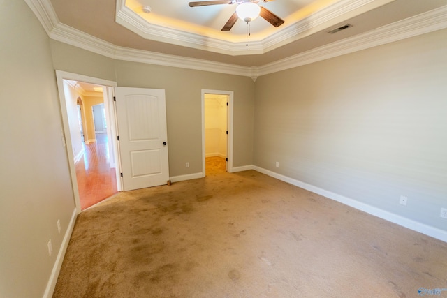 unfurnished bedroom with ceiling fan, ornamental molding, light carpet, a walk in closet, and a closet