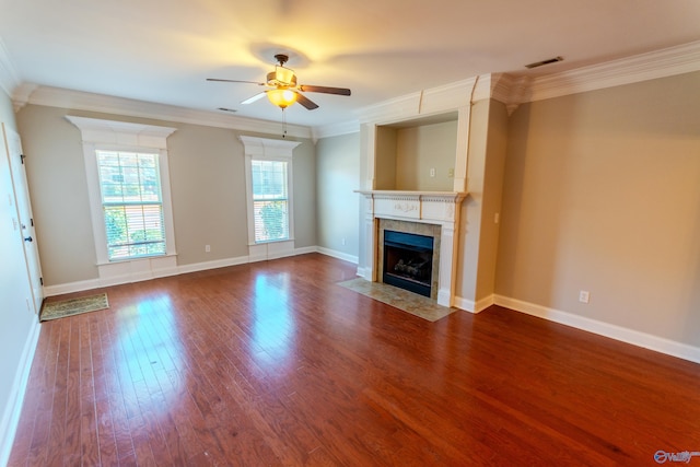 unfurnished living room featuring ceiling fan, wood-type flooring, ornamental molding, and a tiled fireplace