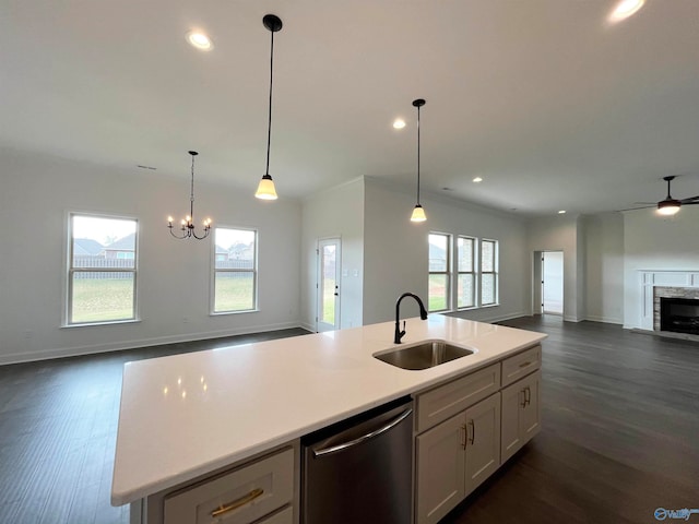 kitchen featuring sink, white cabinetry, dishwasher, an island with sink, and a fireplace